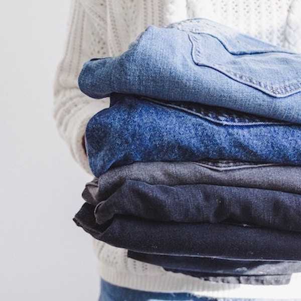 A person holding a pile of folded clothes.